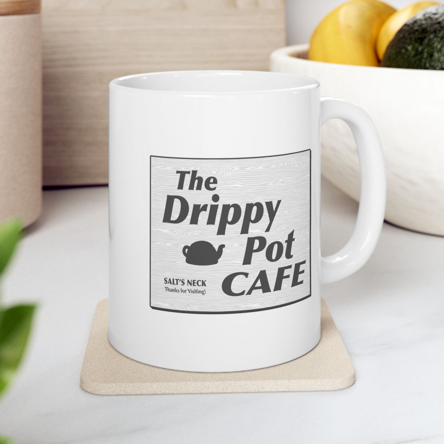 11 oz White Ceramic Mug on a coaster with the Drippy Pot Cafe logo graphic from the TV show Severance