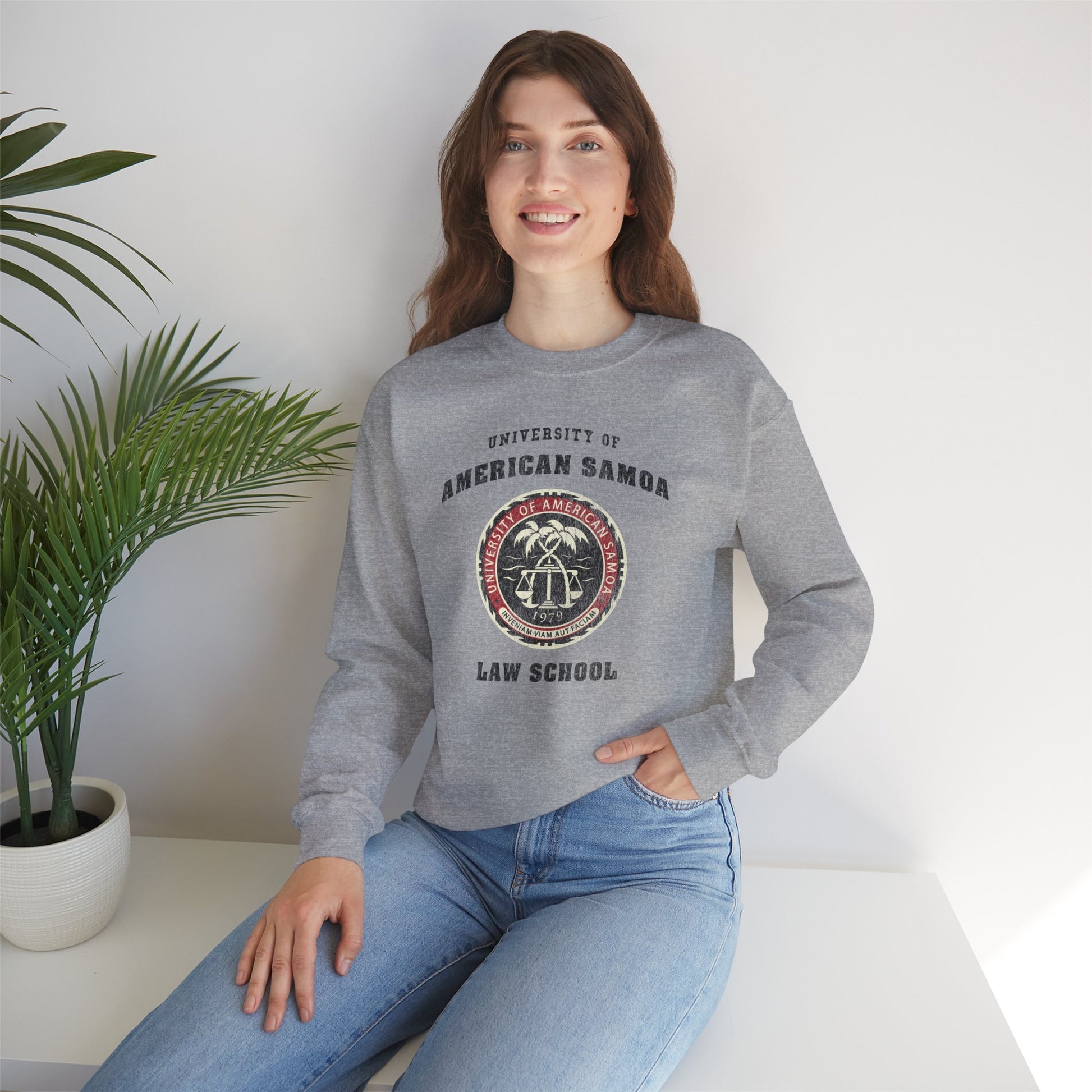 Woman wearing a gray sweatshirt with 'University of American Samoa Law School' text and logo, sitting indoors.