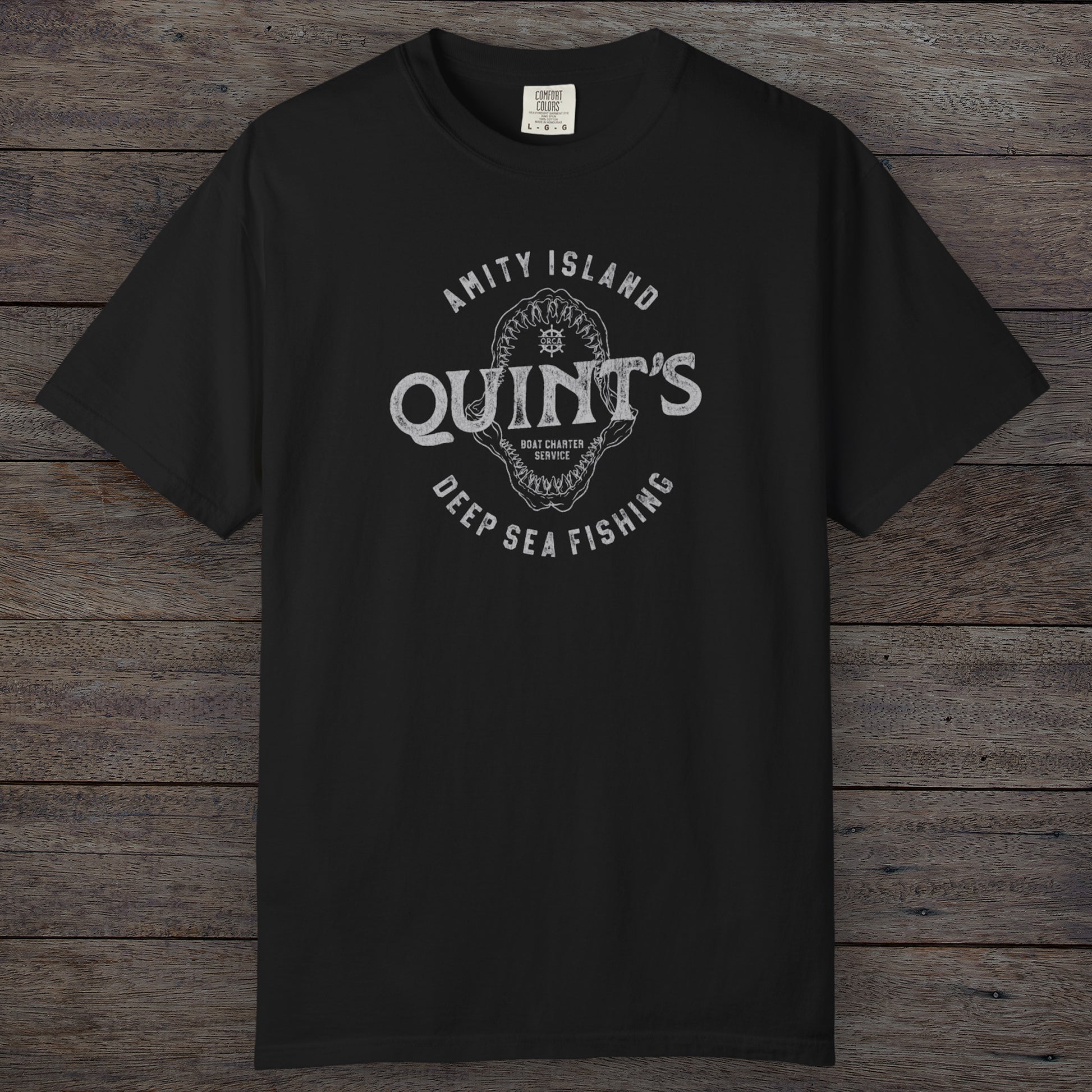 Black Comfort Colors t-shirt with vintage Quint’s Deep Sea Fishing logo from Jaws, featuring shark graphic, distressed style.