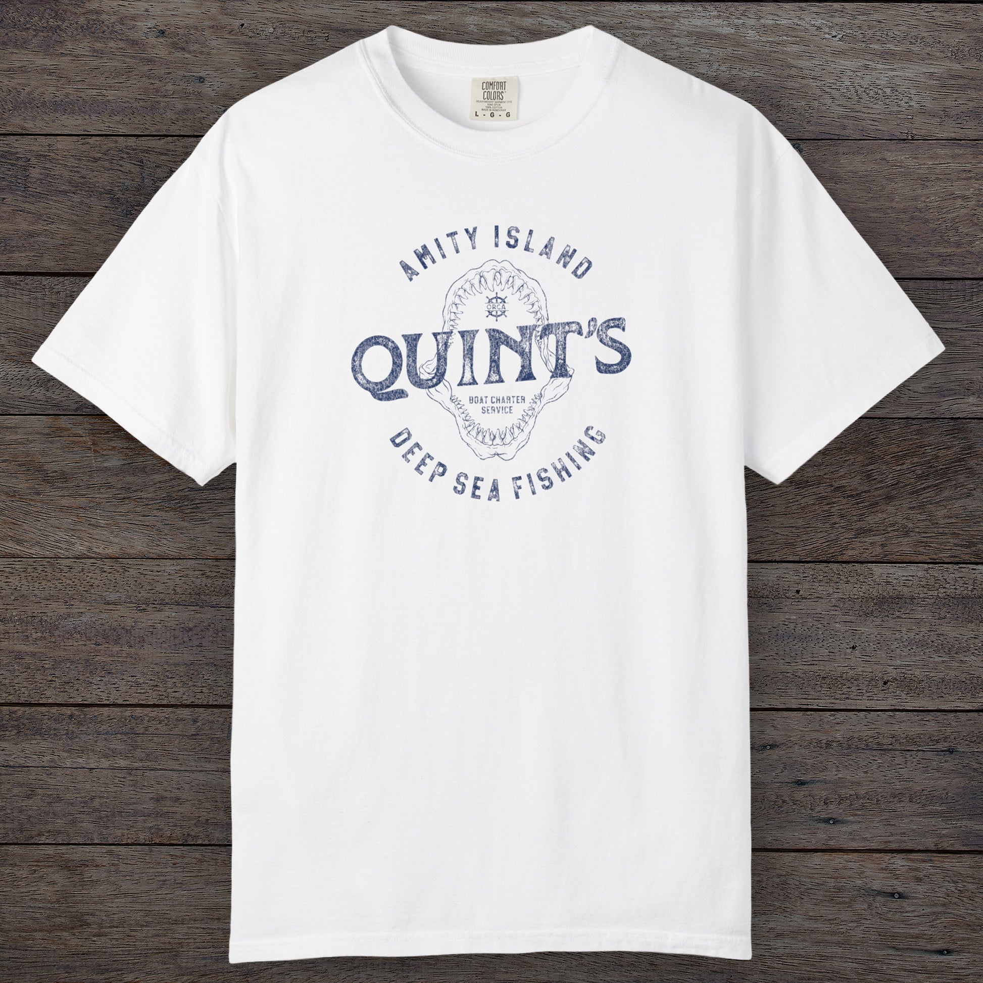 White Comfort Colors t-shirt with vintage Quint’s Deep Sea Fishing logo from Jaws, featuring shark graphic, distressed style.