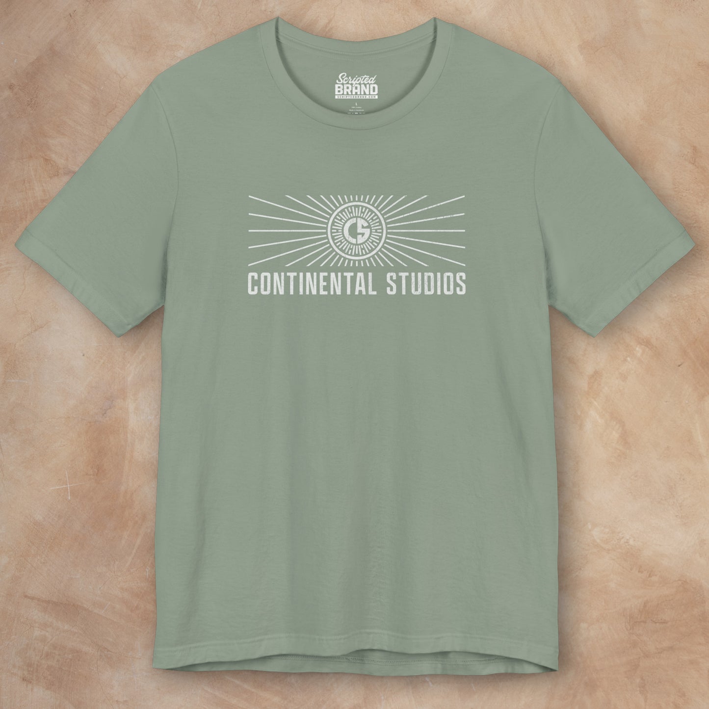 Front view of a sage green colored Soft Bella+Canvas 3001 short-sleeve t-shirt featuring the logo graphic of the fictional movie studio Continental Studios inspired by the Apple TV show The Studio in a vintage distressed style, sold by ScriptedBrand.