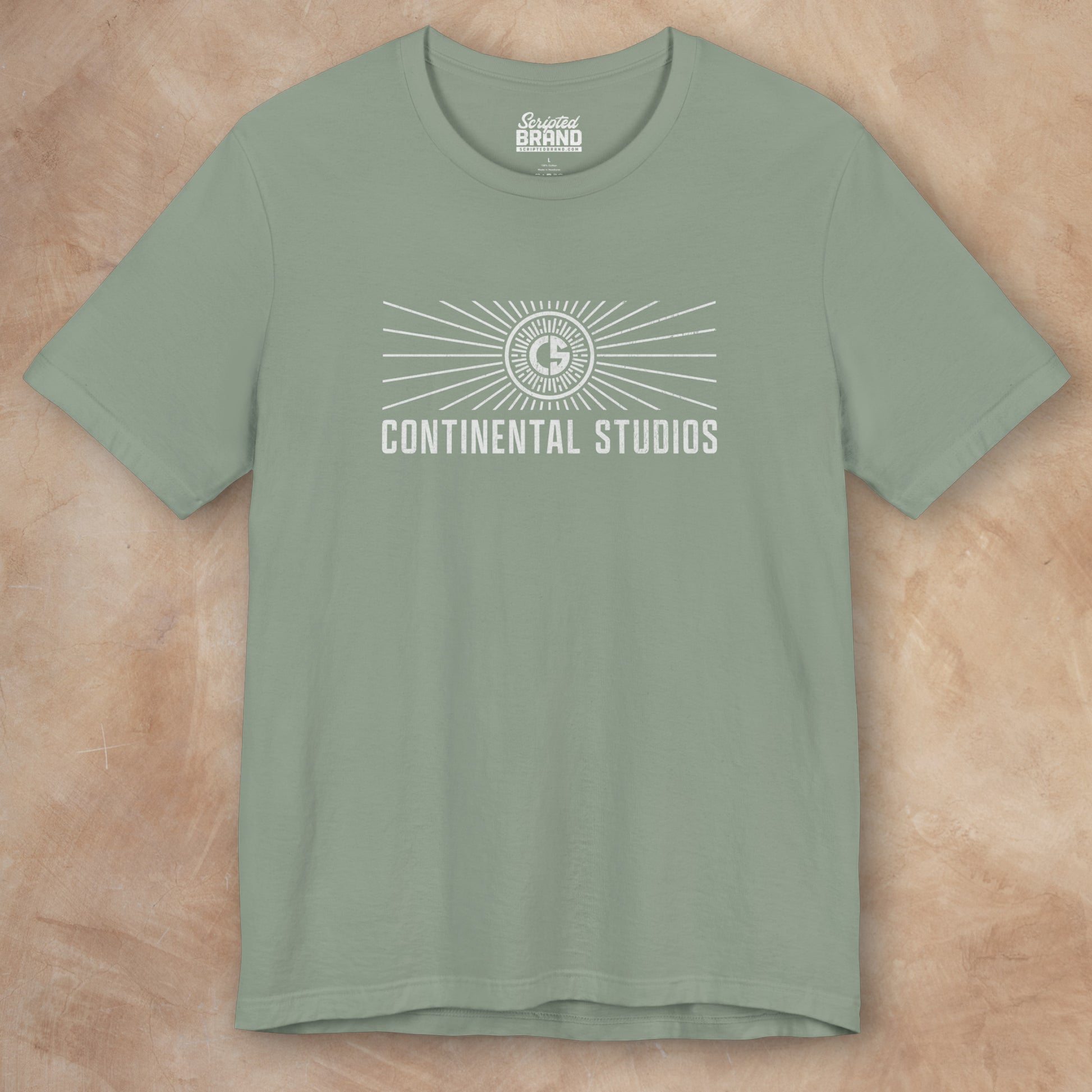 Front view of a sage green colored Soft Bella+Canvas 3001 short-sleeve t-shirt featuring the logo graphic of the fictional movie studio Continental Studios inspired by the Apple TV show The Studio in a vintage distressed style, sold by ScriptedBrand.