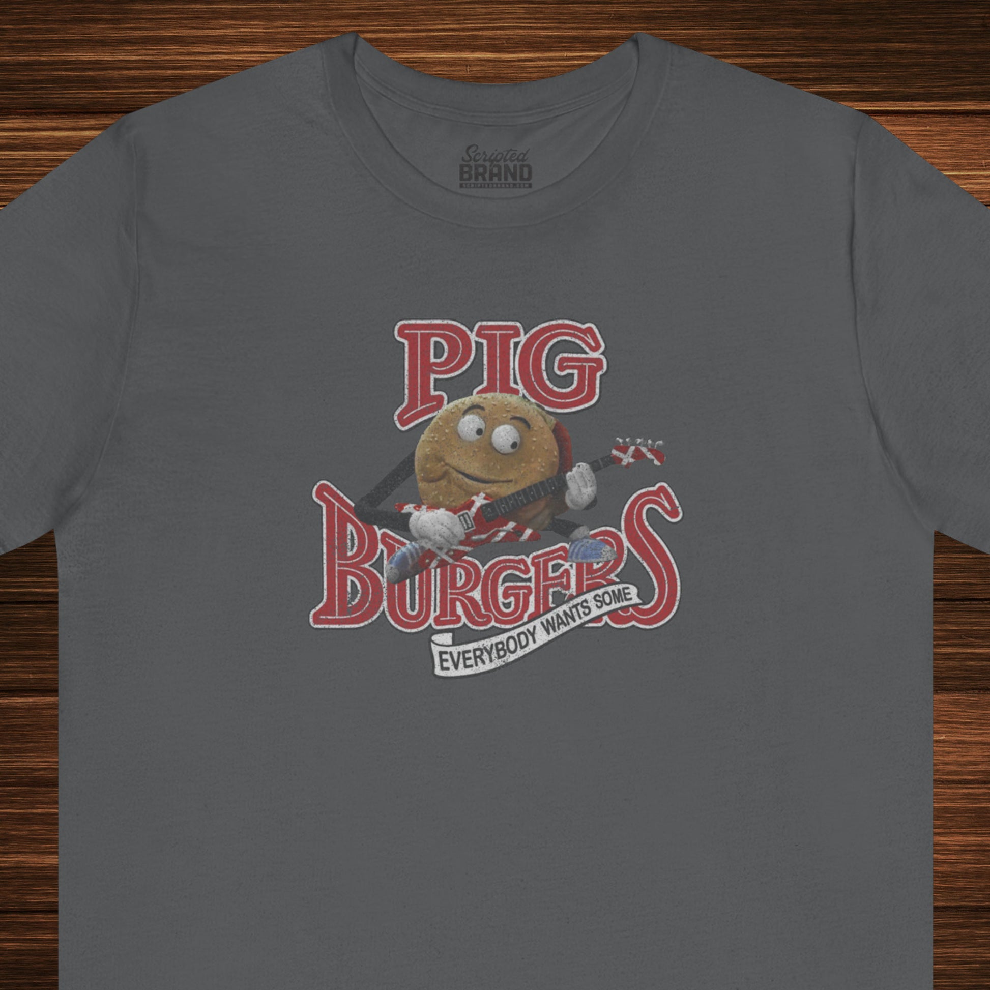 Front view of an asphalt grey colored soft Bella+Canvas 3001 short-sleeve t-shirt featuring a graphic of the fictional Pig Burgers logo from the movie Better Off Dead, along with the Van Halen singing hamburger playing guitar, with the small subhead phrase EVERYBODY WANTS SOME. The graphic is designed in a vintage distressed style, sold by ScriptedBrand.