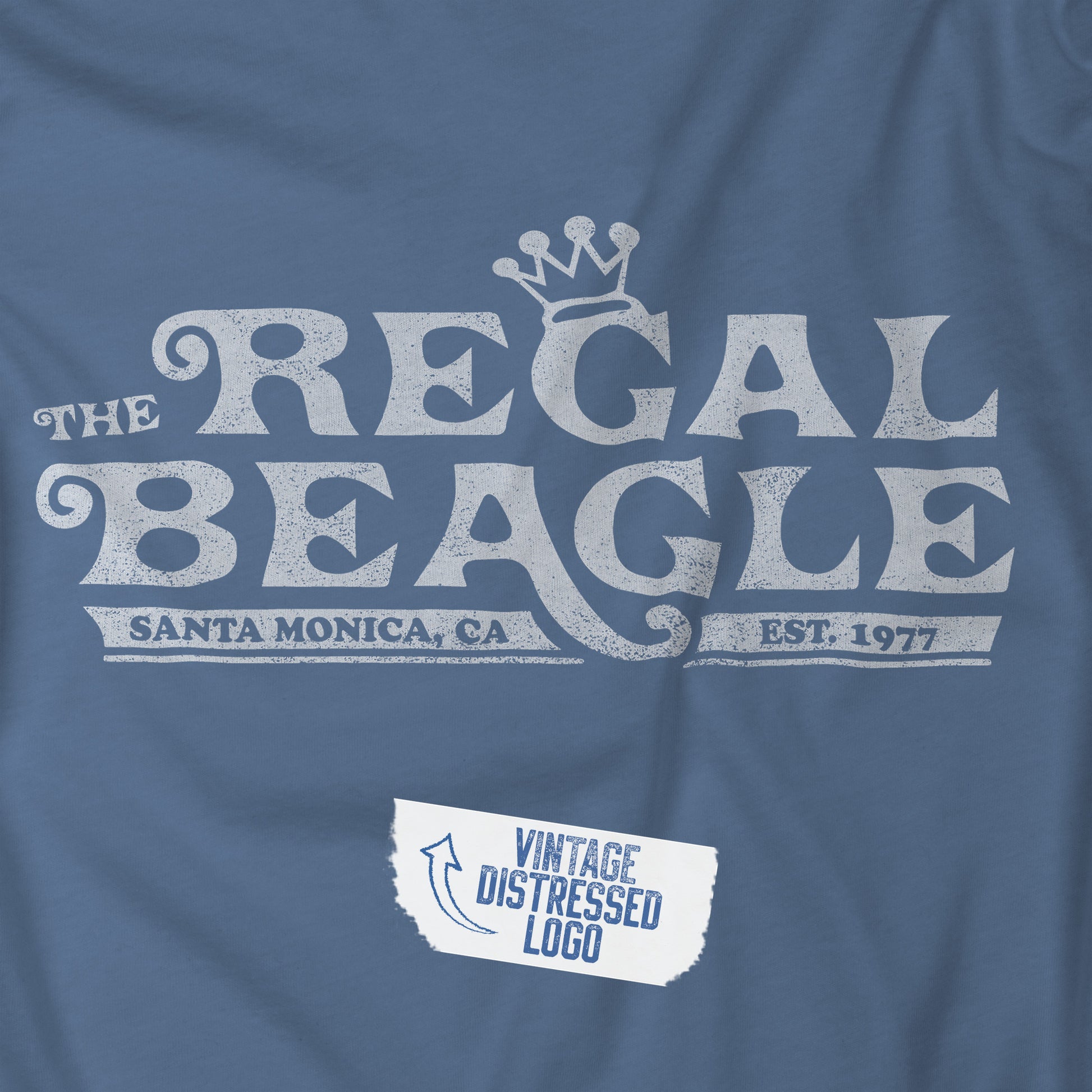 Closeup view of a Lavender Blue colored soft Bella+Canvas 3001 short-sleeve t-shirt featuring the Regal Beagle logo from the TV Show Threes Company in a vintage distressed style.