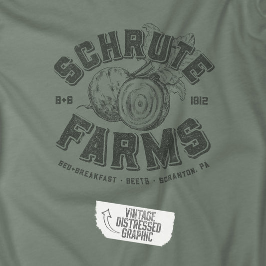 Closeup of Sage green t-shirt featuring a Schrute Farms logo from the TV show The Office designed by ScriptedBrand in a vintage distressed style.
