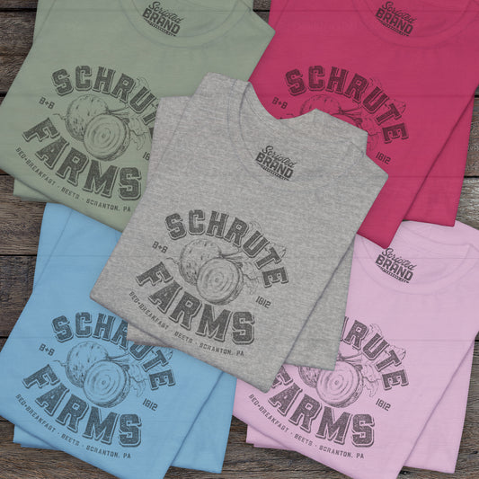 Five folded t-shirts featuring a Schrute Farms logo from the TV show The Office designed by ScriptedBrand in a vintage distressed style.