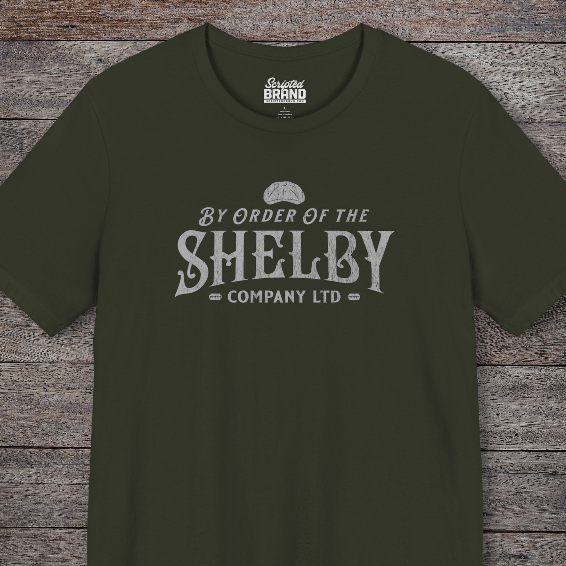 Front view of a dark olive colored soft short-sleeve Bella+Canvas 3001 t-shirt featuring a unique Shelby Company Limited logo graphic from the show Peaky Blinders and movie The Immortal Man, in a vintage distressed style, includes a flat cap and razor blades, designed and sold by ScriptedBrand.