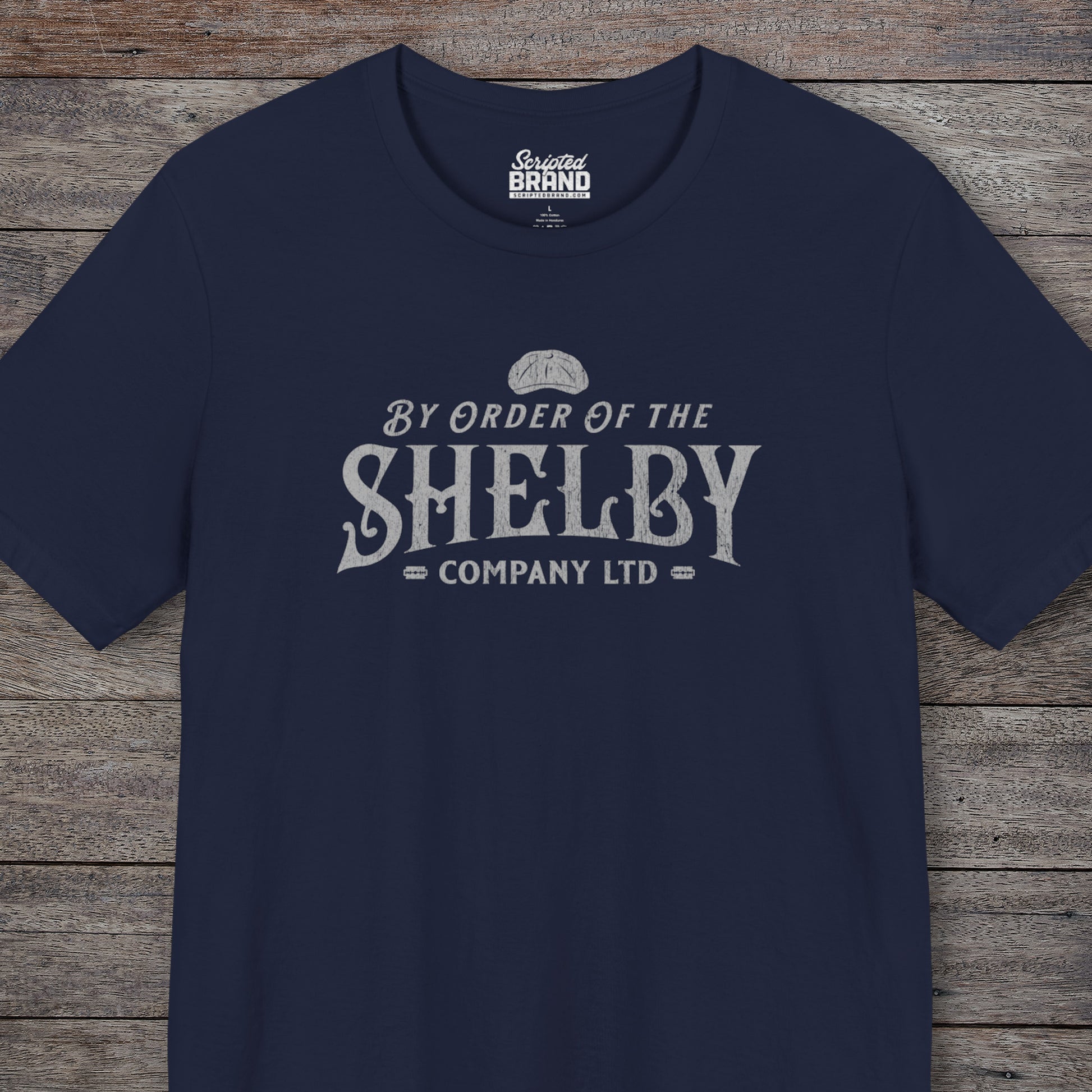 Front view of a Navy blue colored soft short-sleeve Bella+Canvas 3001 t-shirt featuring a unique Shelby Company Limited logo graphic from the show Peaky Blinders and movie The Immortal Man, in a vintage distressed style, includes a flat cap and razor blades, designed and sold by ScriptedBrand.