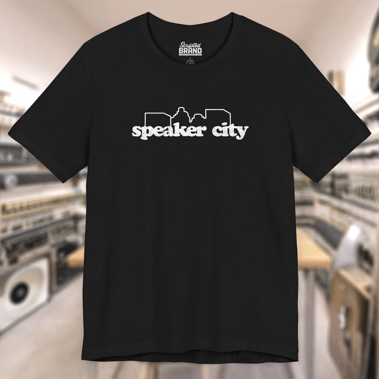 Front view of black t-shirt featuring the Speaker City logo from the movie Old School in a vintage distressed style with white print and skyline outline.