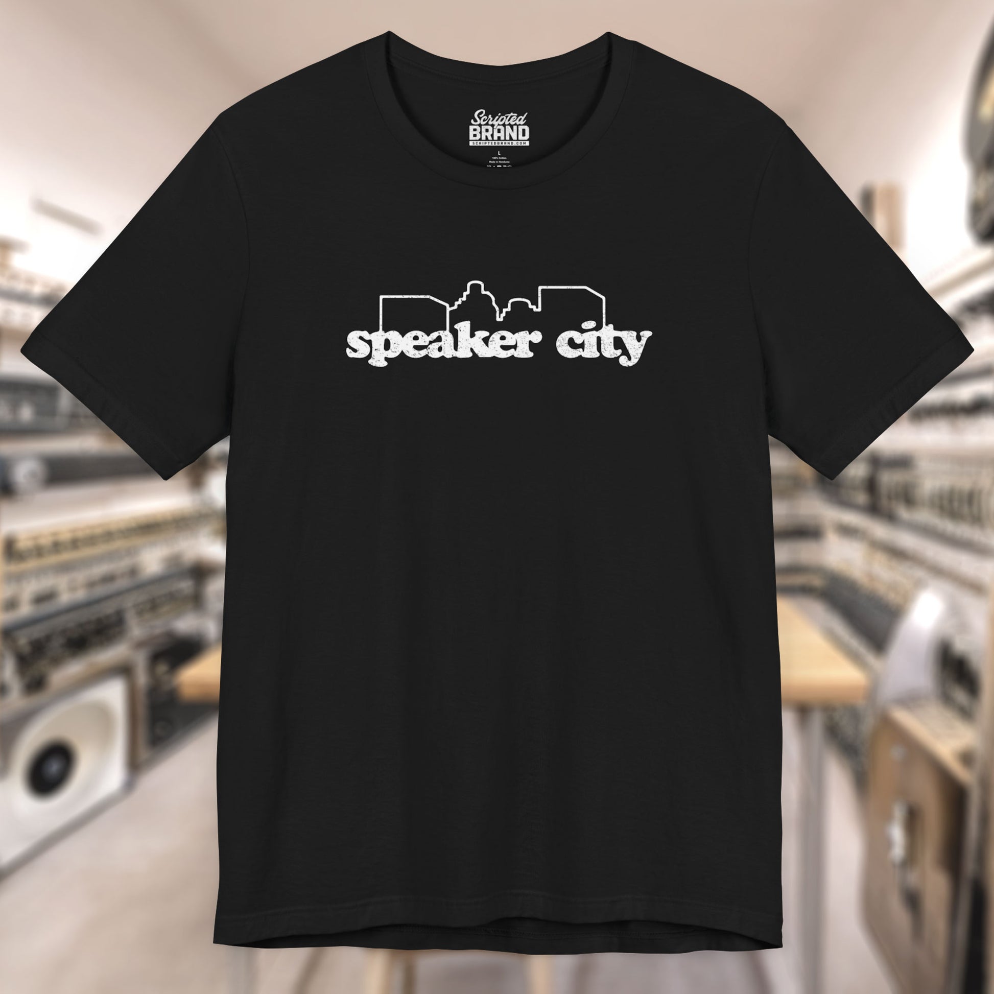 Front view of black t-shirt featuring the Speaker City logo from the movie Old School in a vintage distressed style with white print and skyline outline.