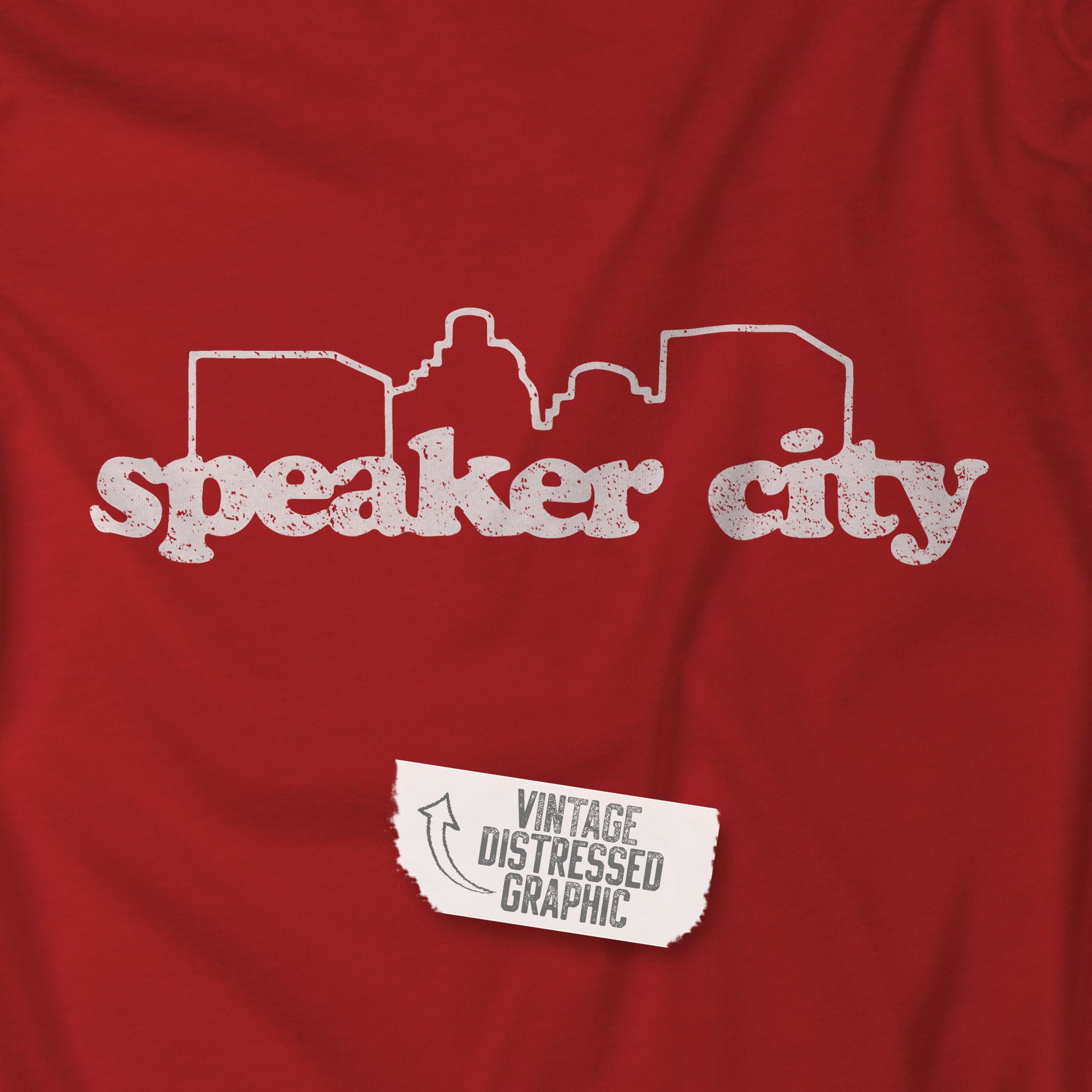 Closeup of red t-shirt featuring the Speaker City logo from the movie Old School in a vintage distressed style with white print and skyline outline.