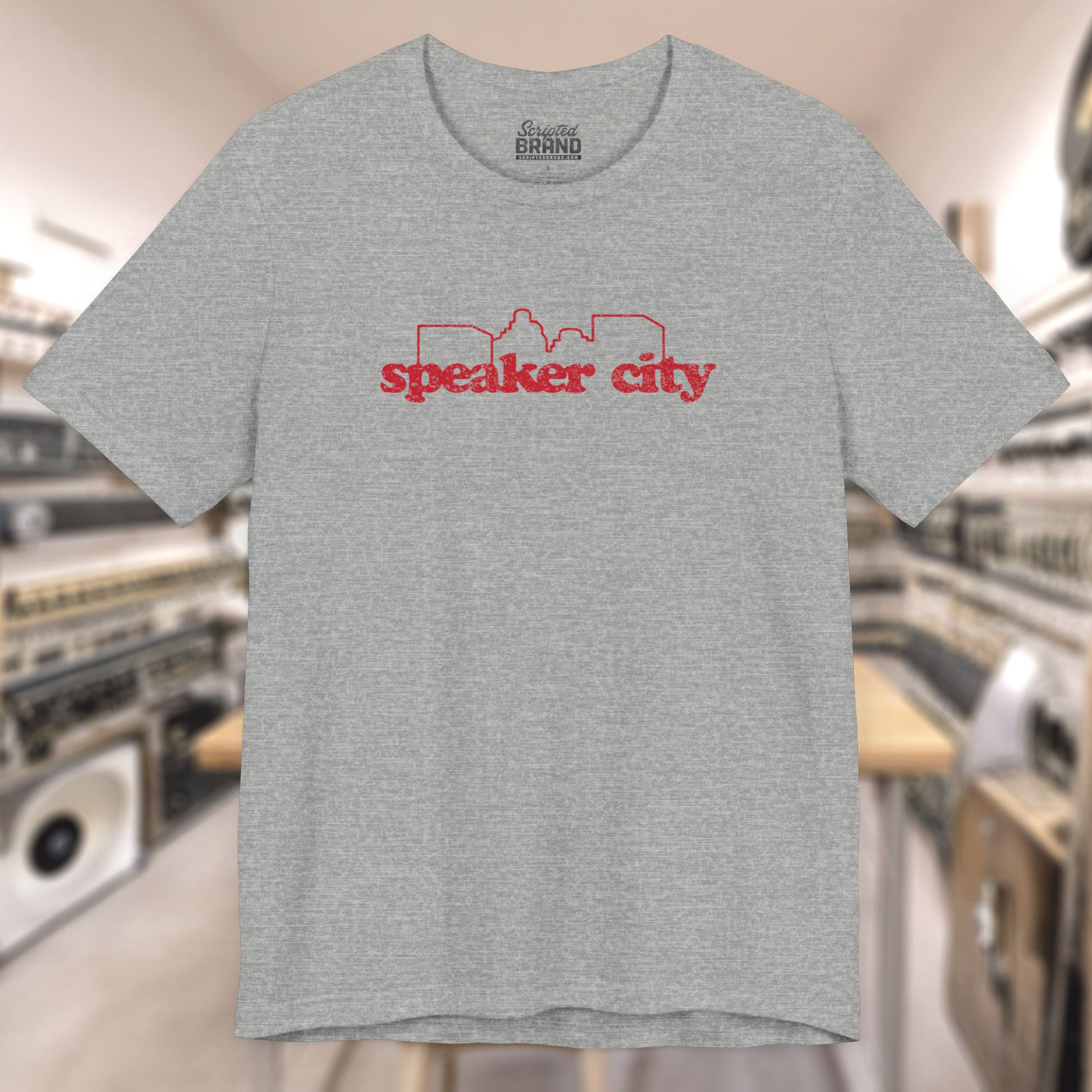 Front view of grey t-shirt featuring the Speaker City logo from the movie Old School in a vintage distressed style with red print and skyline outline.