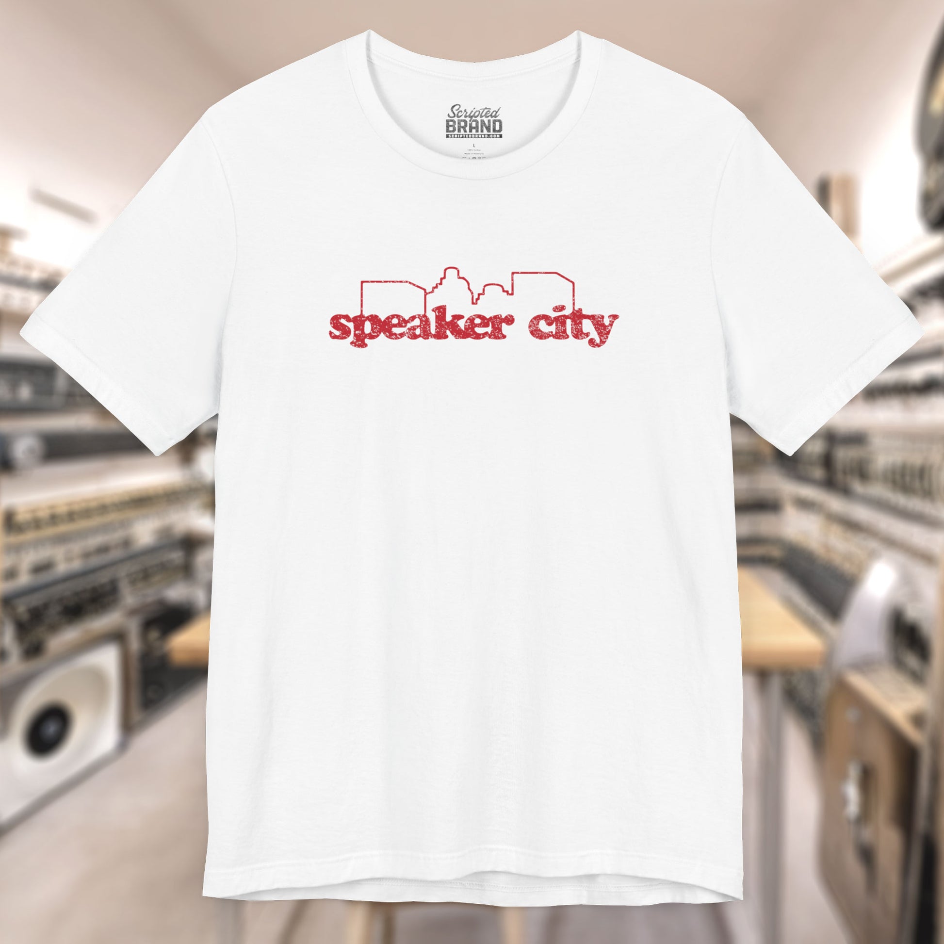 Front view of white t-shirt featuring the Speaker City logo from the movie Old School in a vintage distressed style with red print and skyline outline.