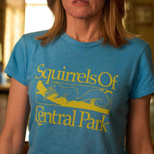 Eva Garvey of the show Bad Sisters wearing a blue t-shirt with 'Squirrels Of Central Park' text and graphic.